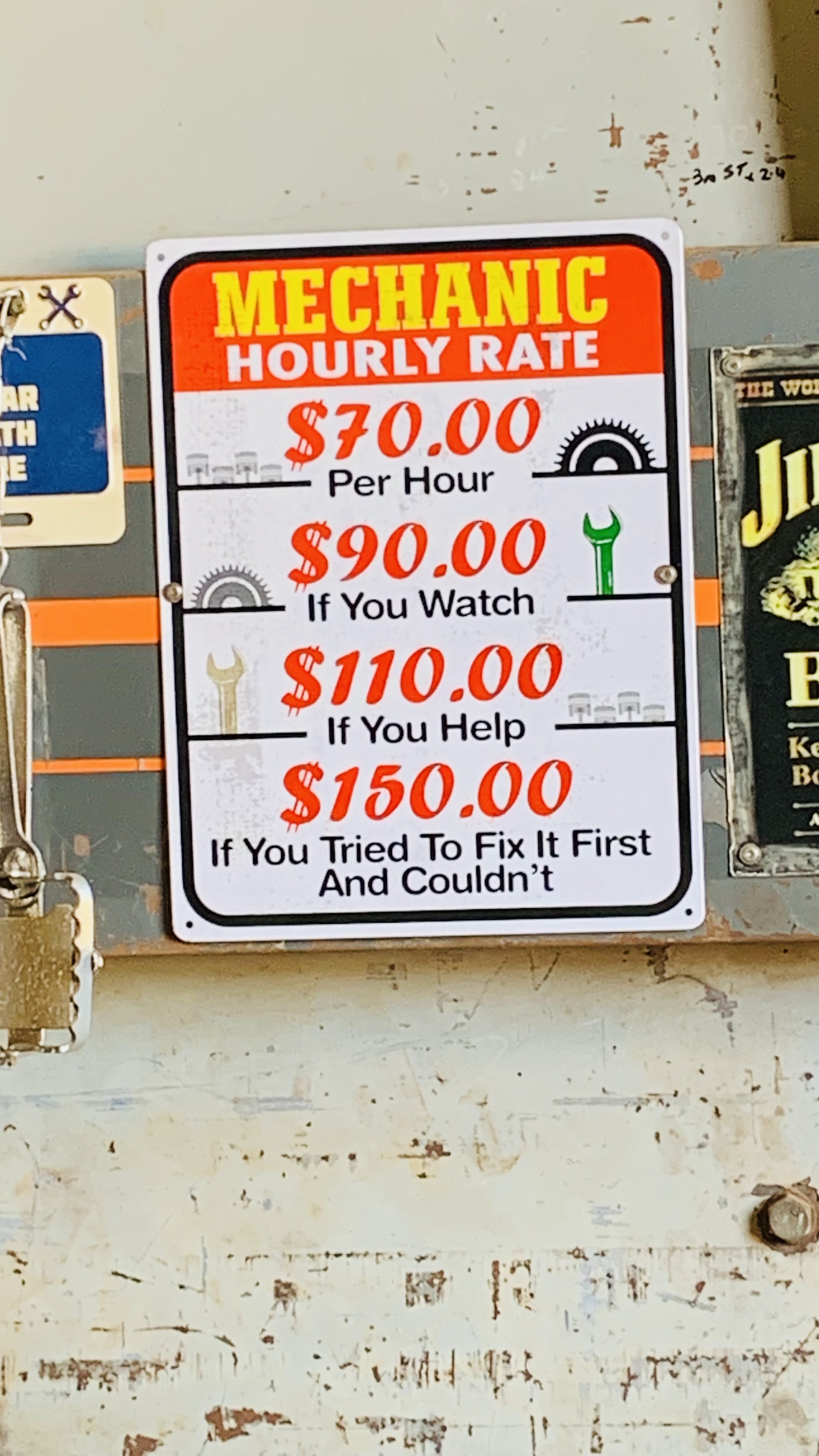 A hand painted sign inside the workshop listing the mechanic hourly rate, rising if you watch or help